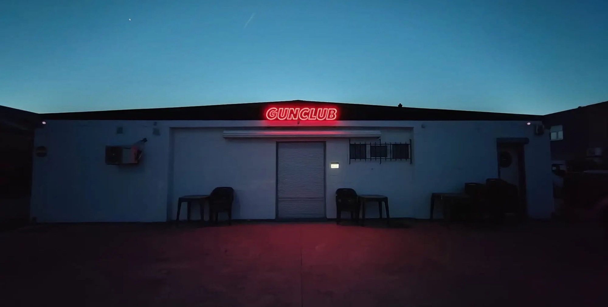 Façade du Gun Club au crépuscule, enseigne néon rouge GUNCLUB