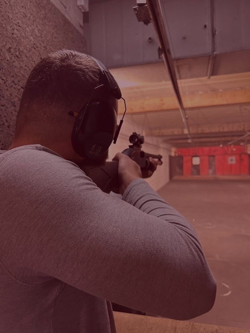 Tireur encadré par un moniteur sur le stand du Gun Club, ambiance rouge